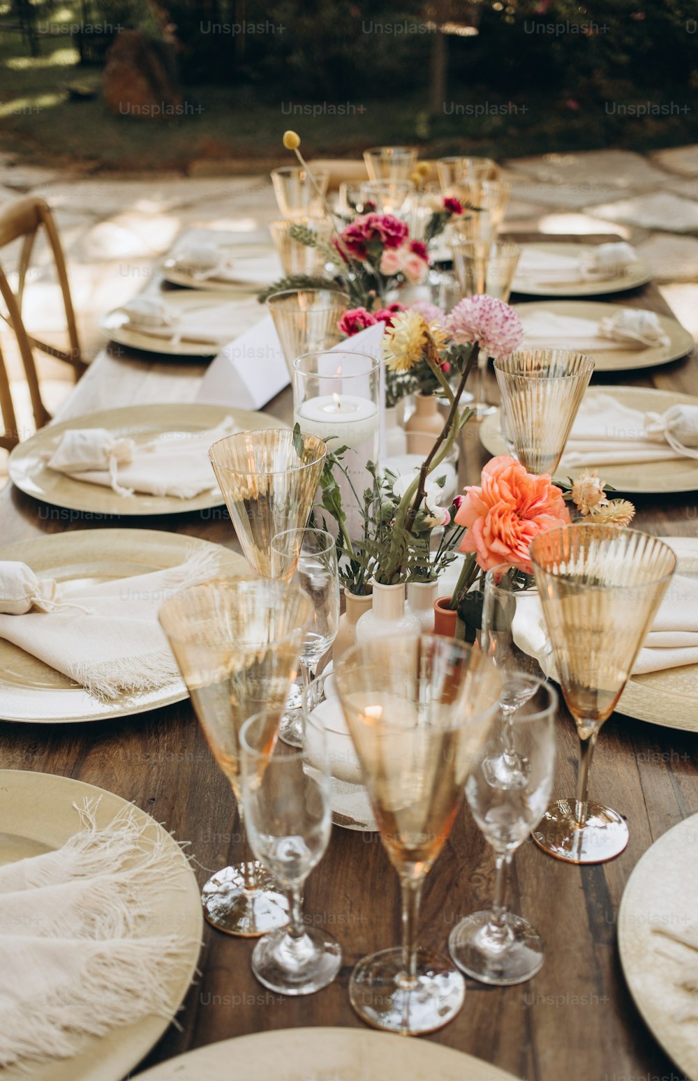 una lunga tavola apparecchiata con bicchieri e piatti da champagne