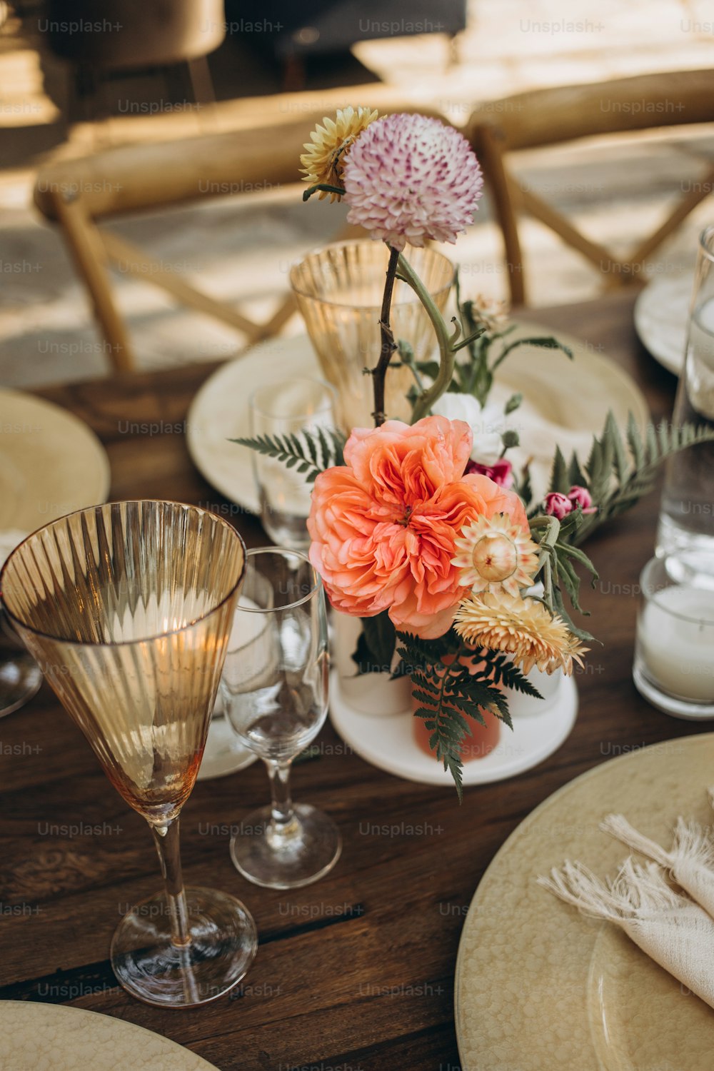 a wooden table topped with plates and vases filled with flowers