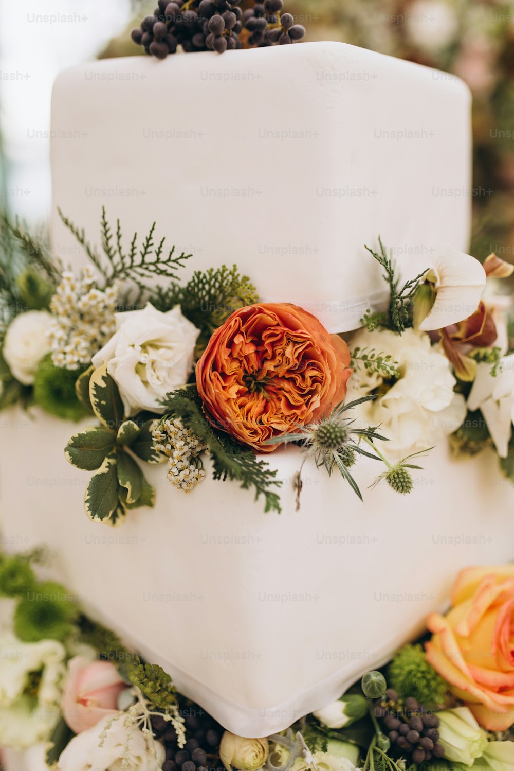 um bolo de casamento com flores e vegetação no topo