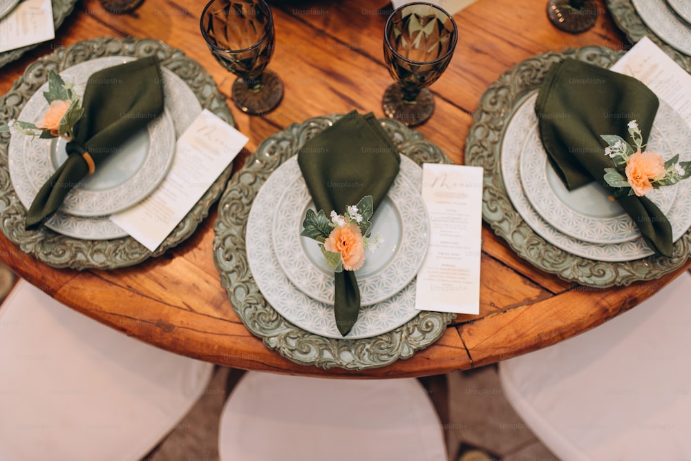 a wooden table topped with plates and place settings