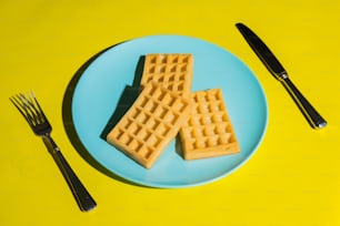 two waffles on a plate with a fork and knife