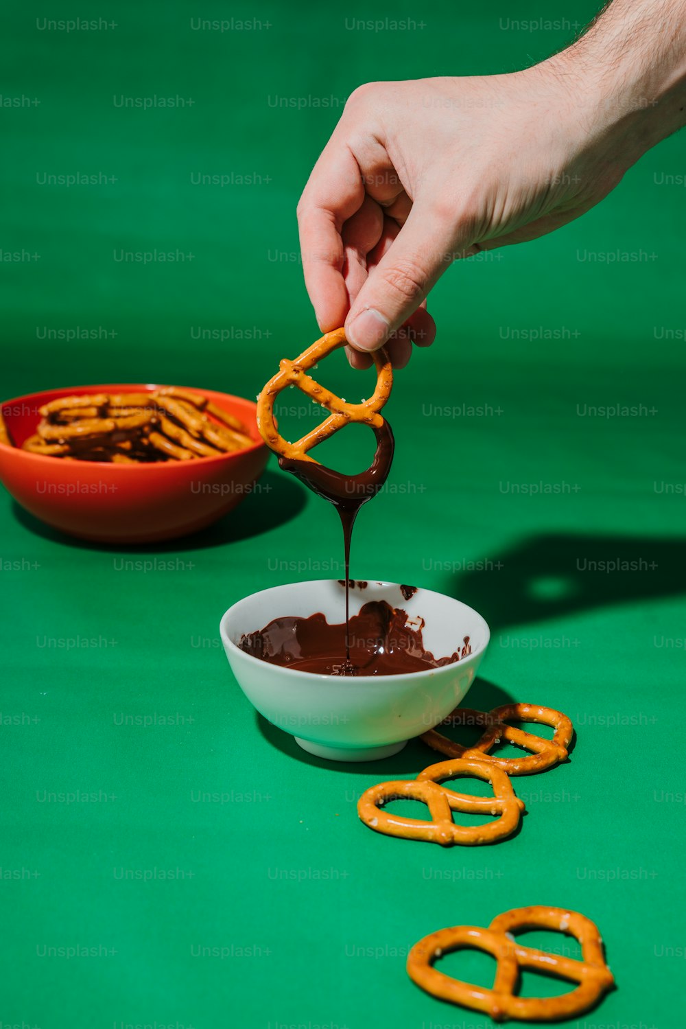 Una persona sumergiendo chocolate en un tazón de pretzels
