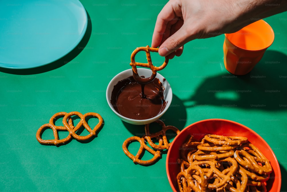 uma tigela de pretzels sendo mergulhados com chocolate