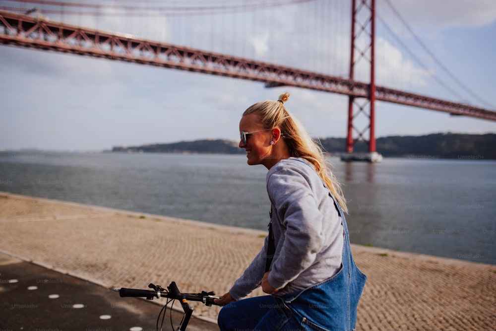 a woman riding a bike next to a body of water