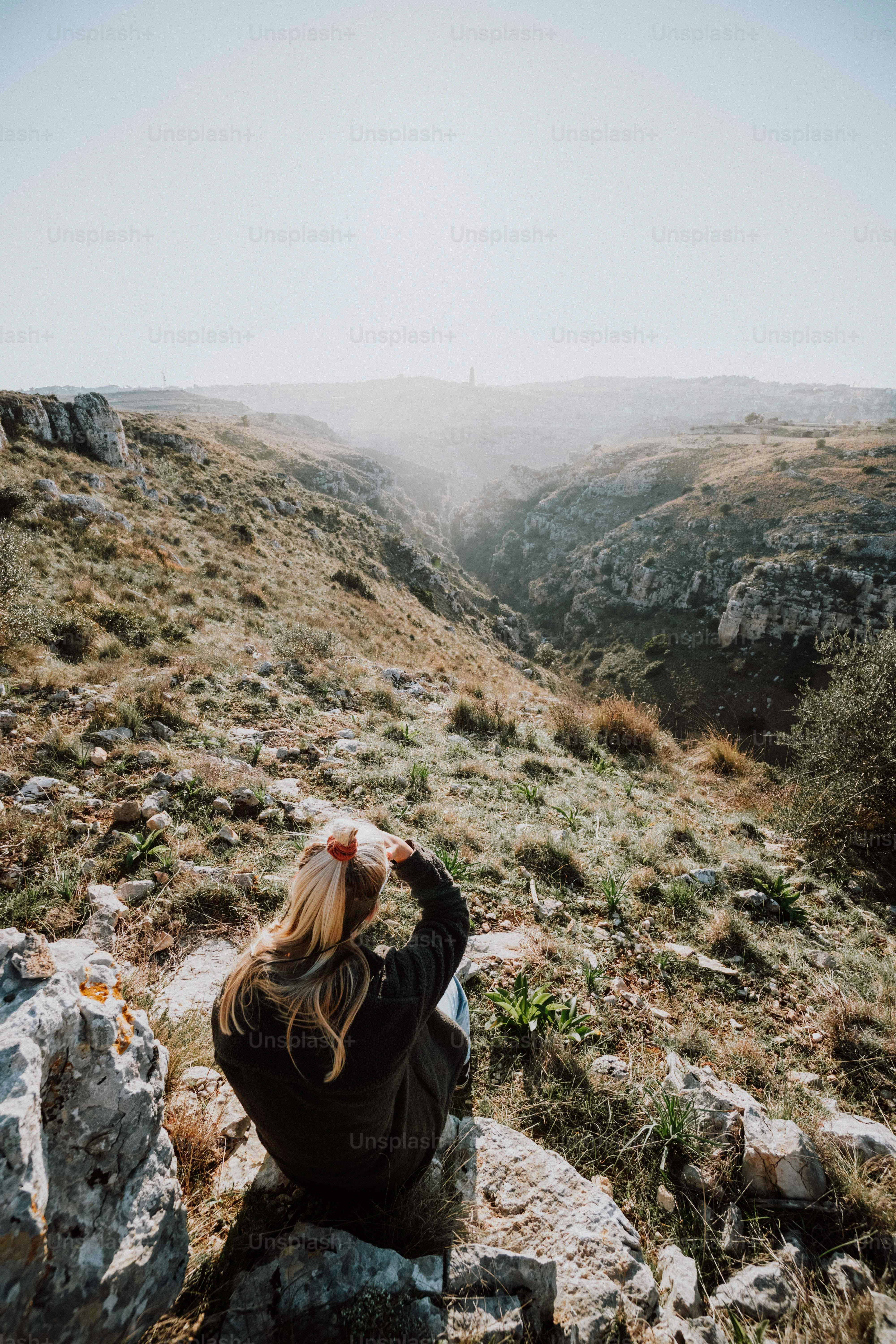 a woman sitting on top of a rocky hillside