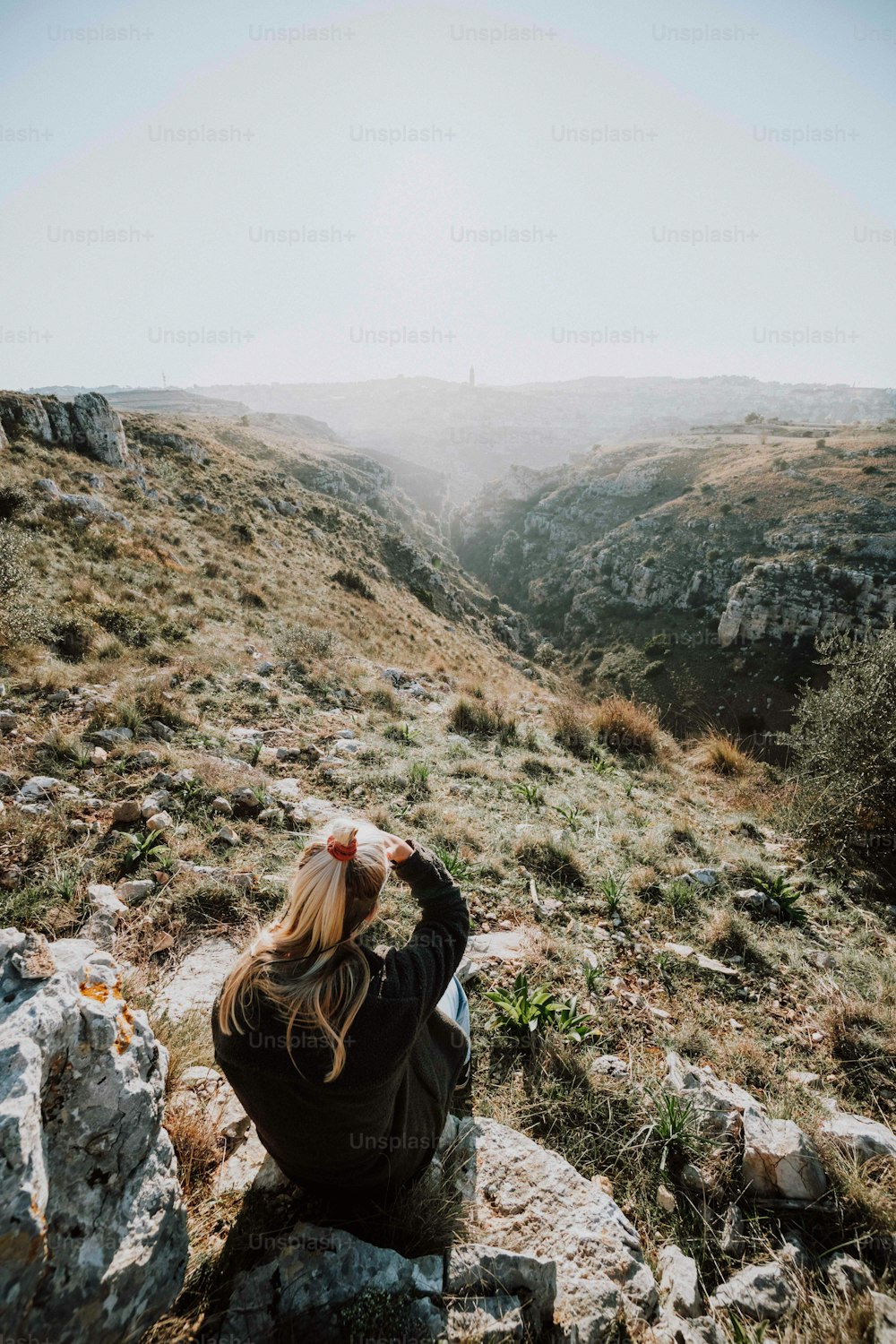 岩だらけの丘の中腹に座っている女性