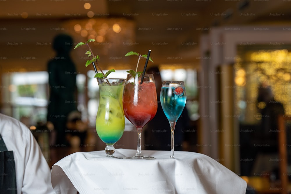 Tres vasos de bebidas de diferentes colores en una mesa