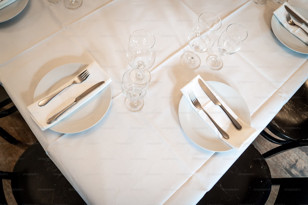uma mesa com uma toalha de mesa branca e talheres