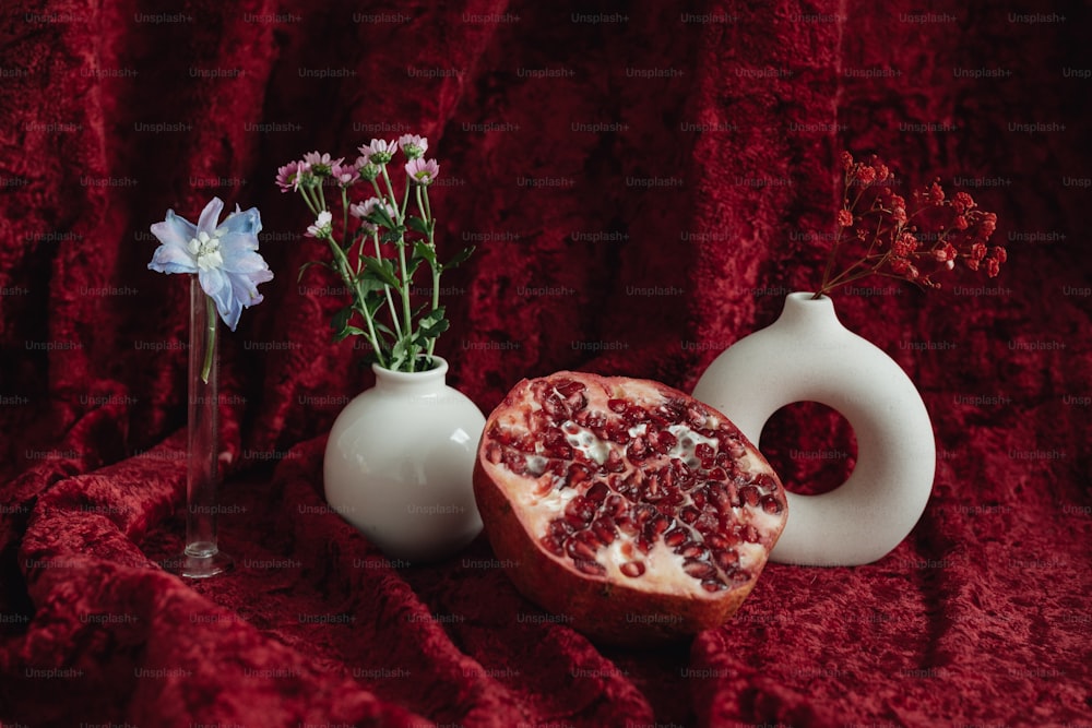 a pomegranate and a vase on a red cloth