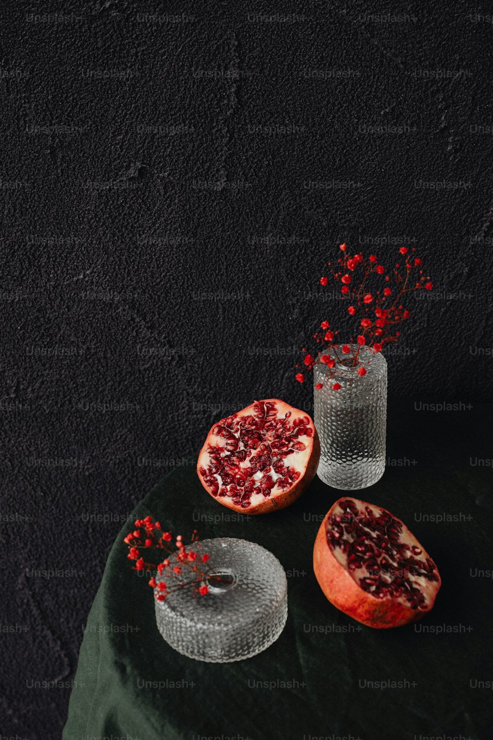 two pomegranates and a glass on a table