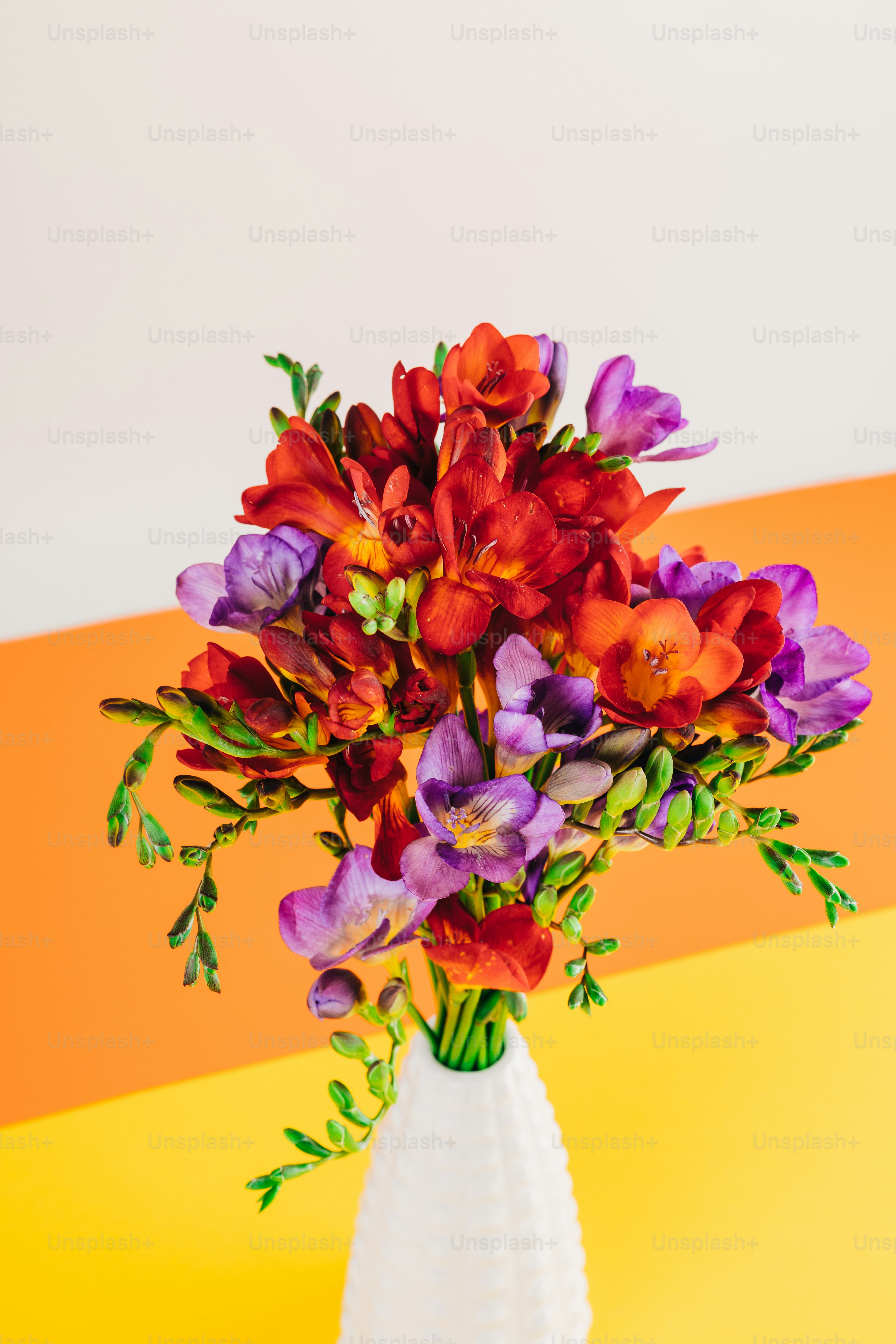 a white vase filled with purple and red flowers
