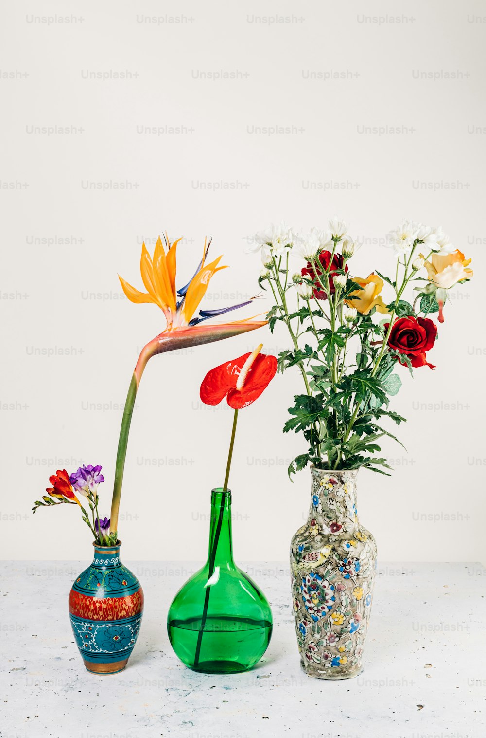 Tres jarrones con flores en ellos sobre una mesa