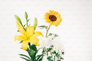 eine Vase gefüllt mit gelben und weißen Blumen
