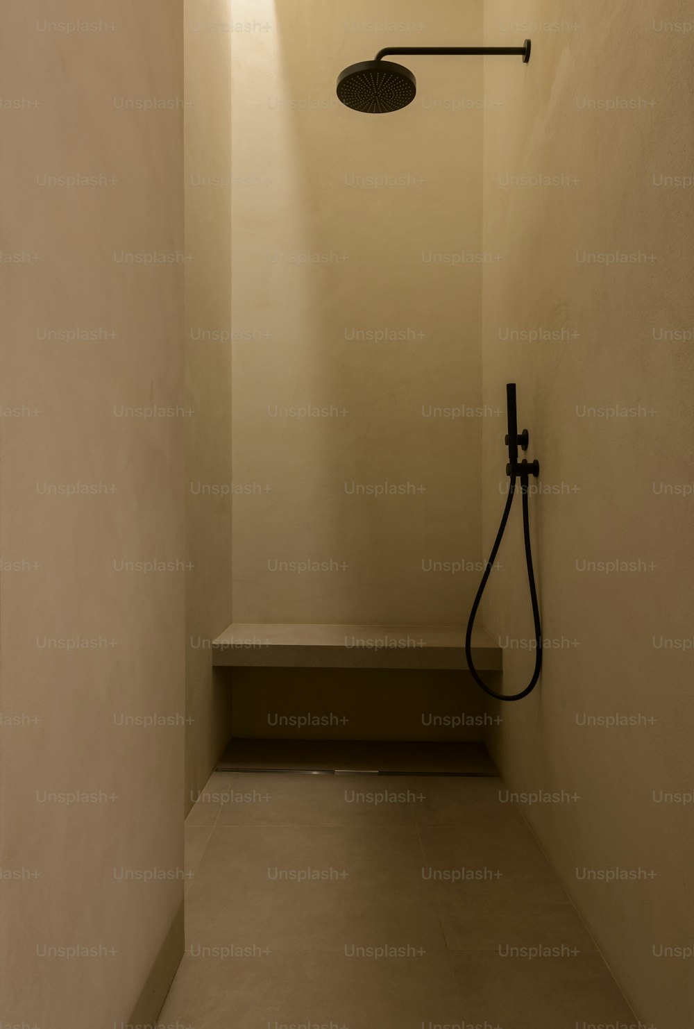 a bathroom with a black shower head and a white wall