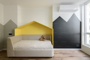 un lit avec une tête de lit jaune et un ours en peluche