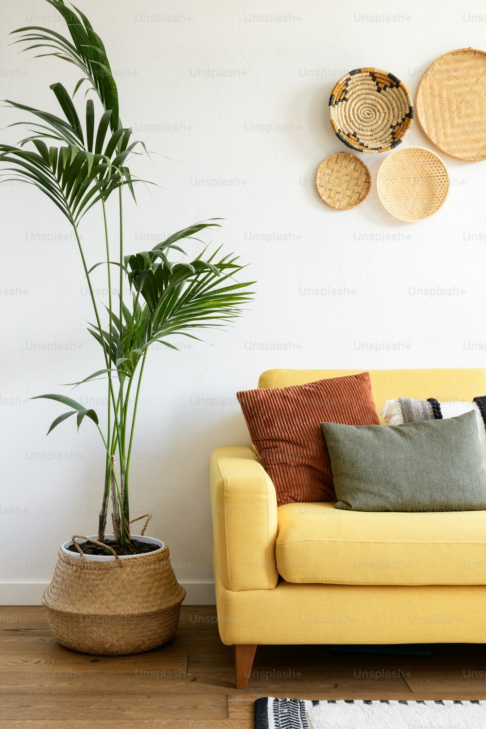 uma sala de estar com um sofá amarelo e um vaso de plantas