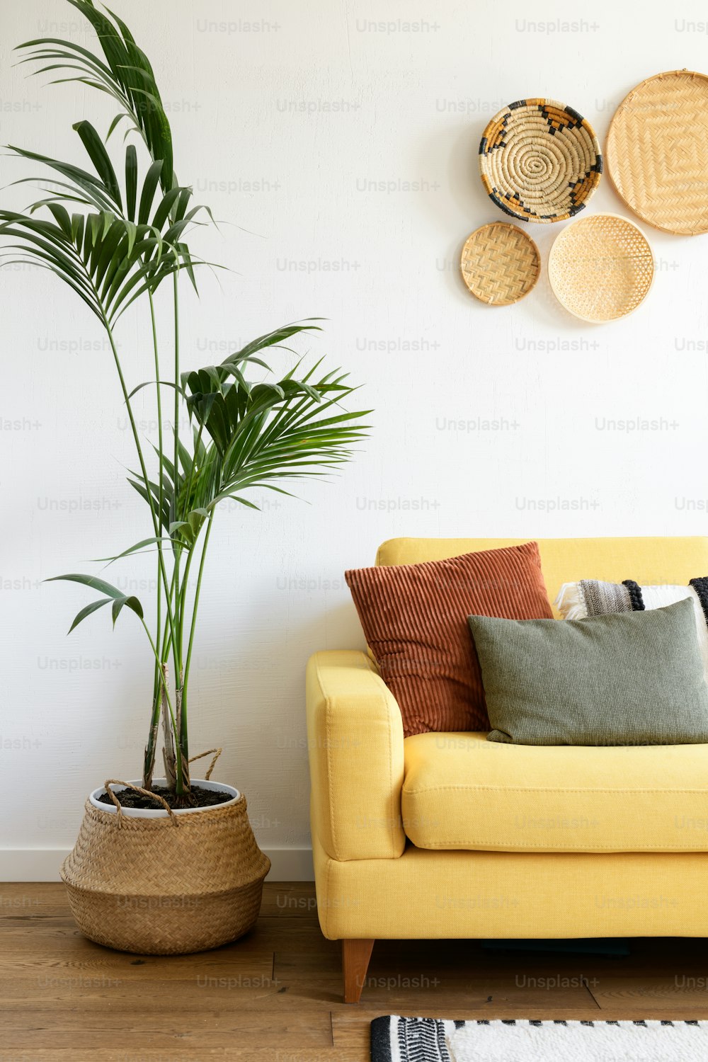 a living room with a yellow couch and a potted plant