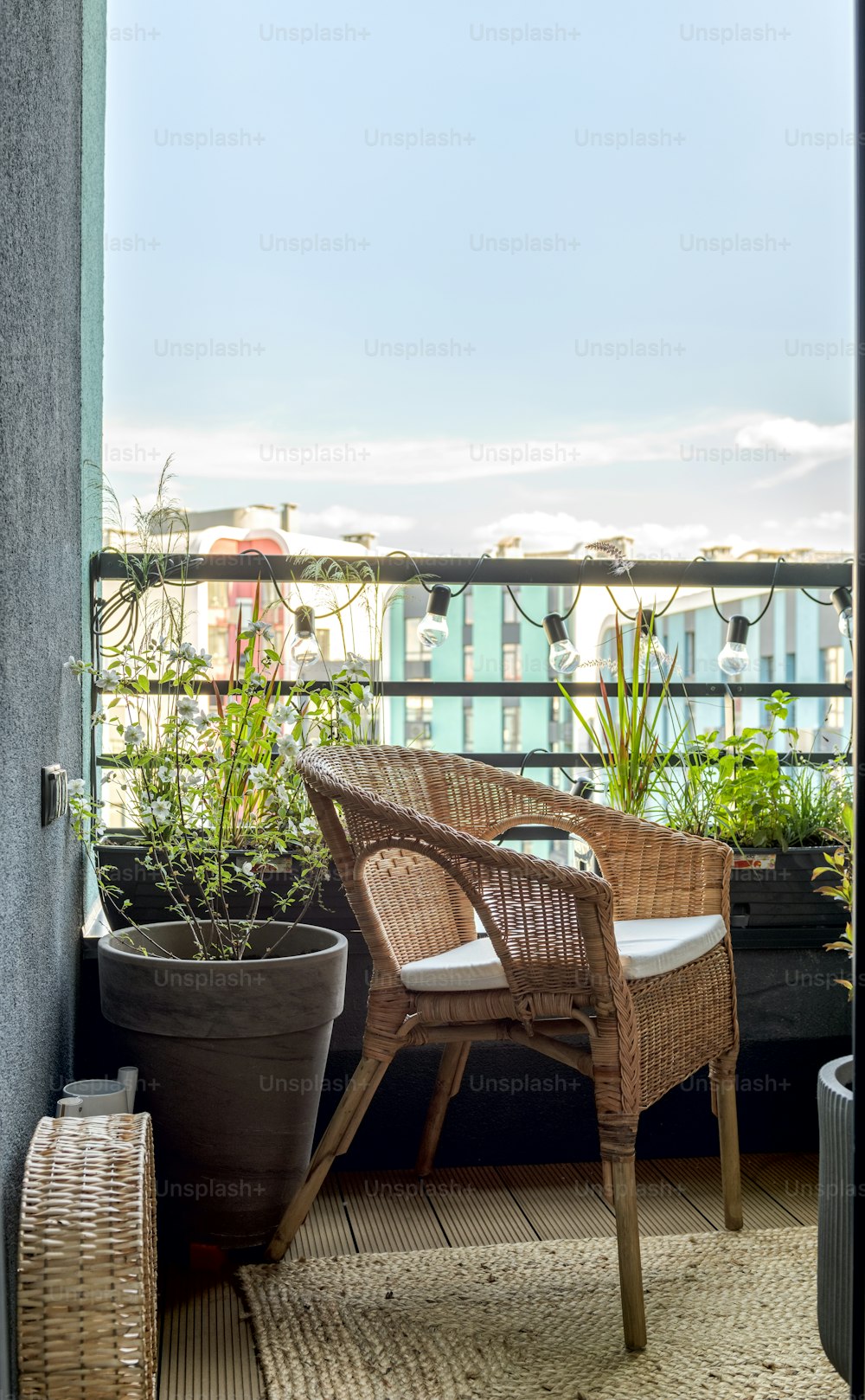 uma cadeira de vime sentada em uma varanda ao lado de um vaso de plantas