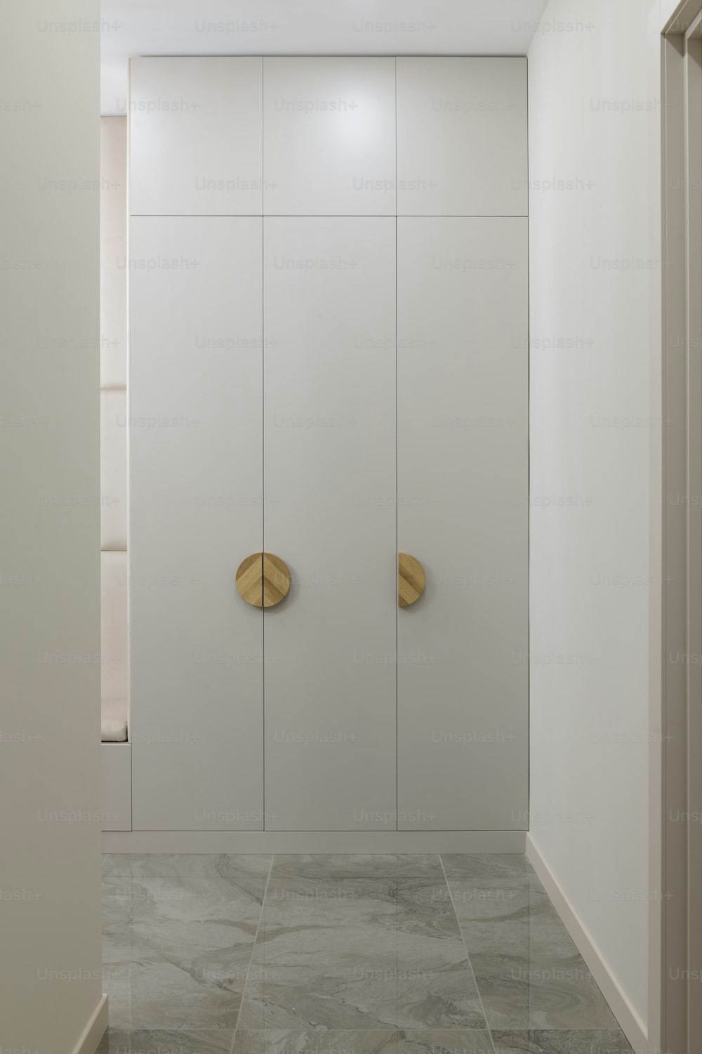a bathroom with a white wall and two gold doors