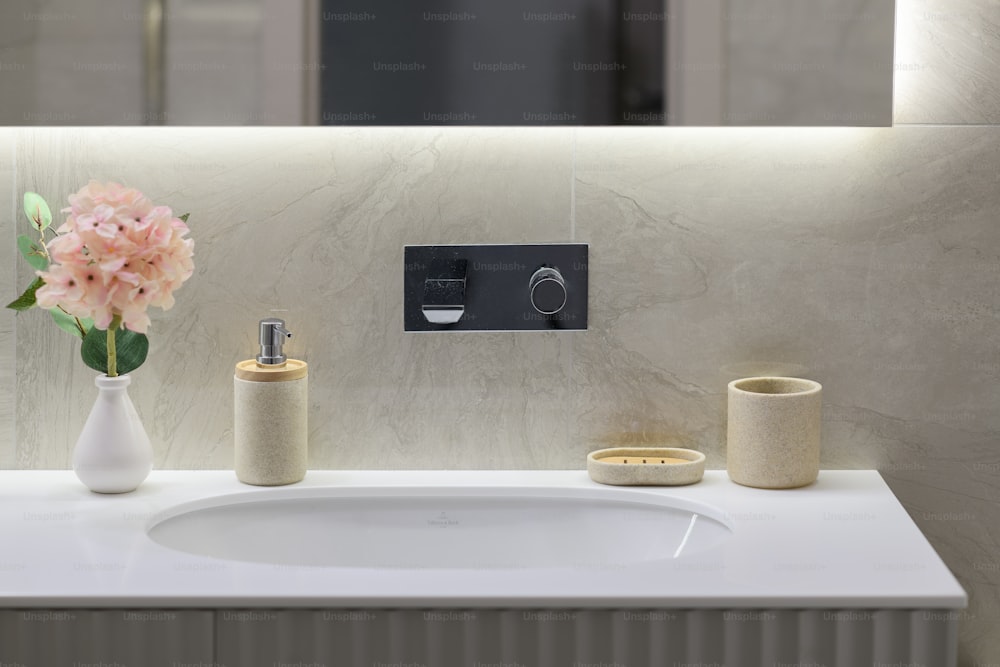 a bathroom with a sink, soap dispenser and a vase with flowers