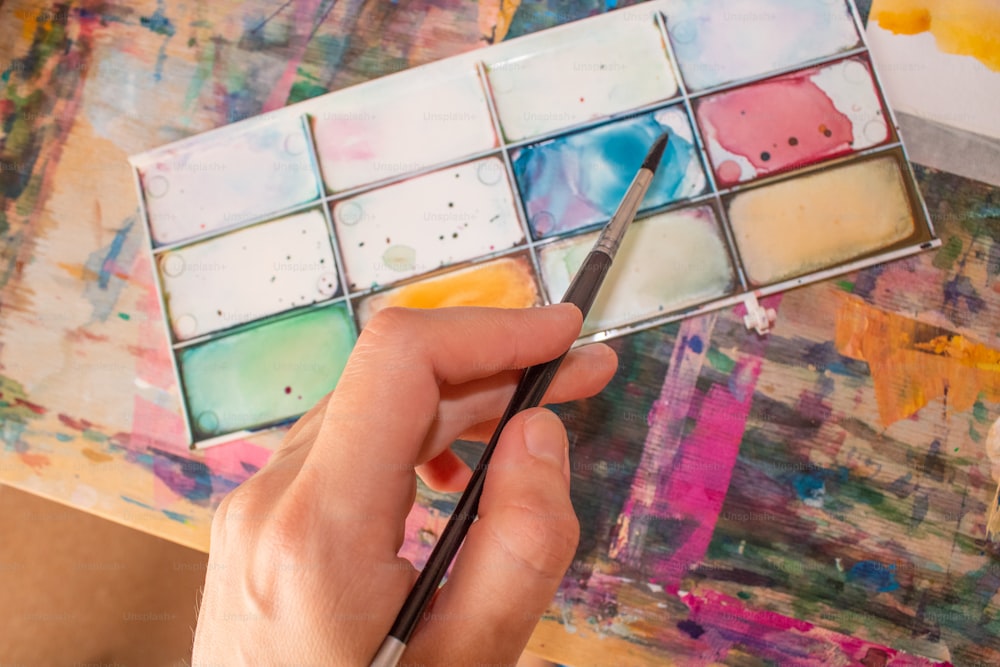 a person holding a paintbrush in front of a painting