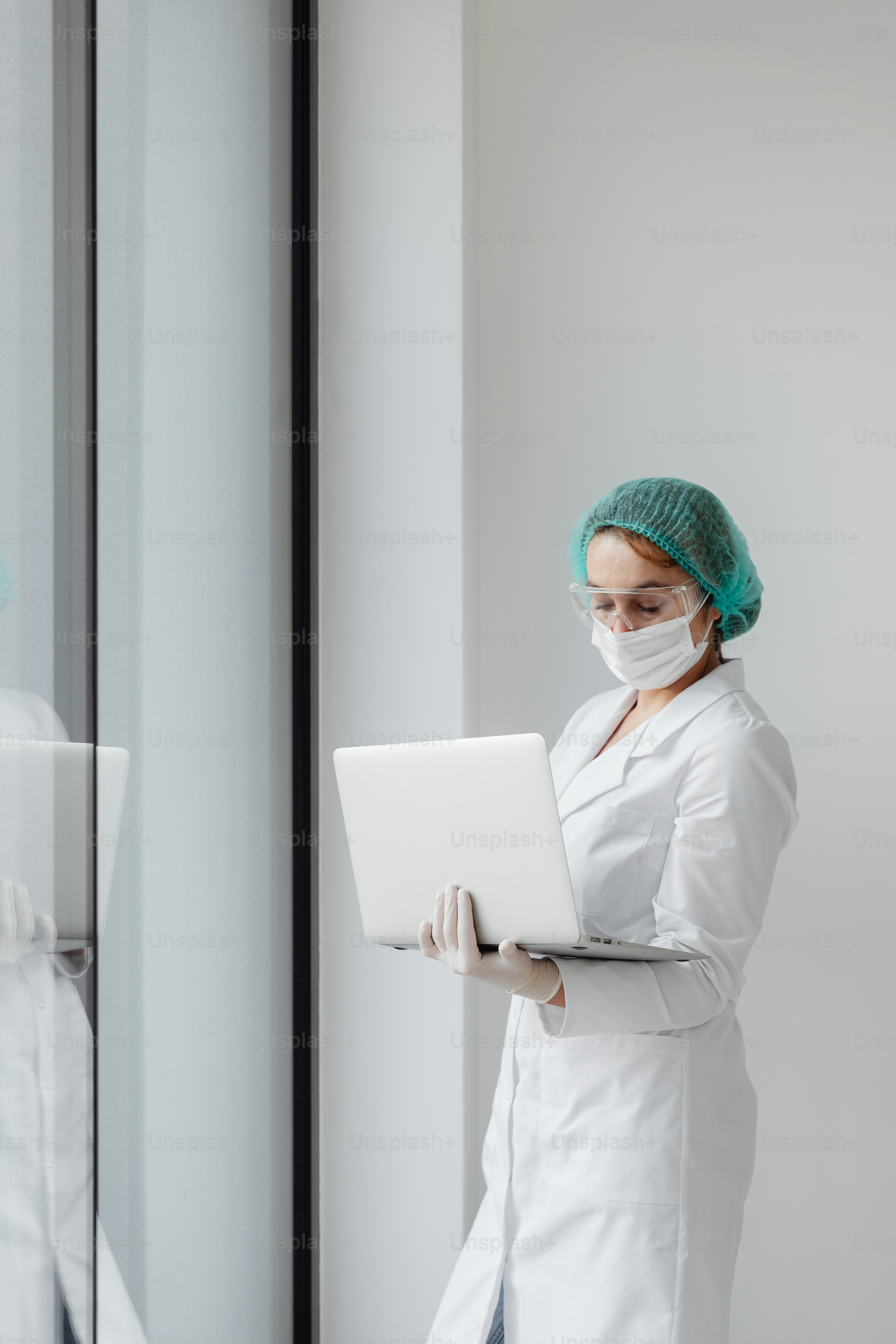 Una mujer con una bata blanca de laboratorio está usando una computadora portátil