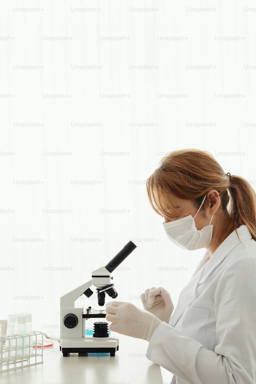 a woman in a white lab coat looking at a microscope