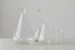 3つのガラスの花瓶と計量カップで覆われた白いテーブル