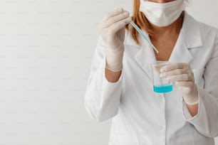 a woman in a white lab coat holding a glass of blue liquid