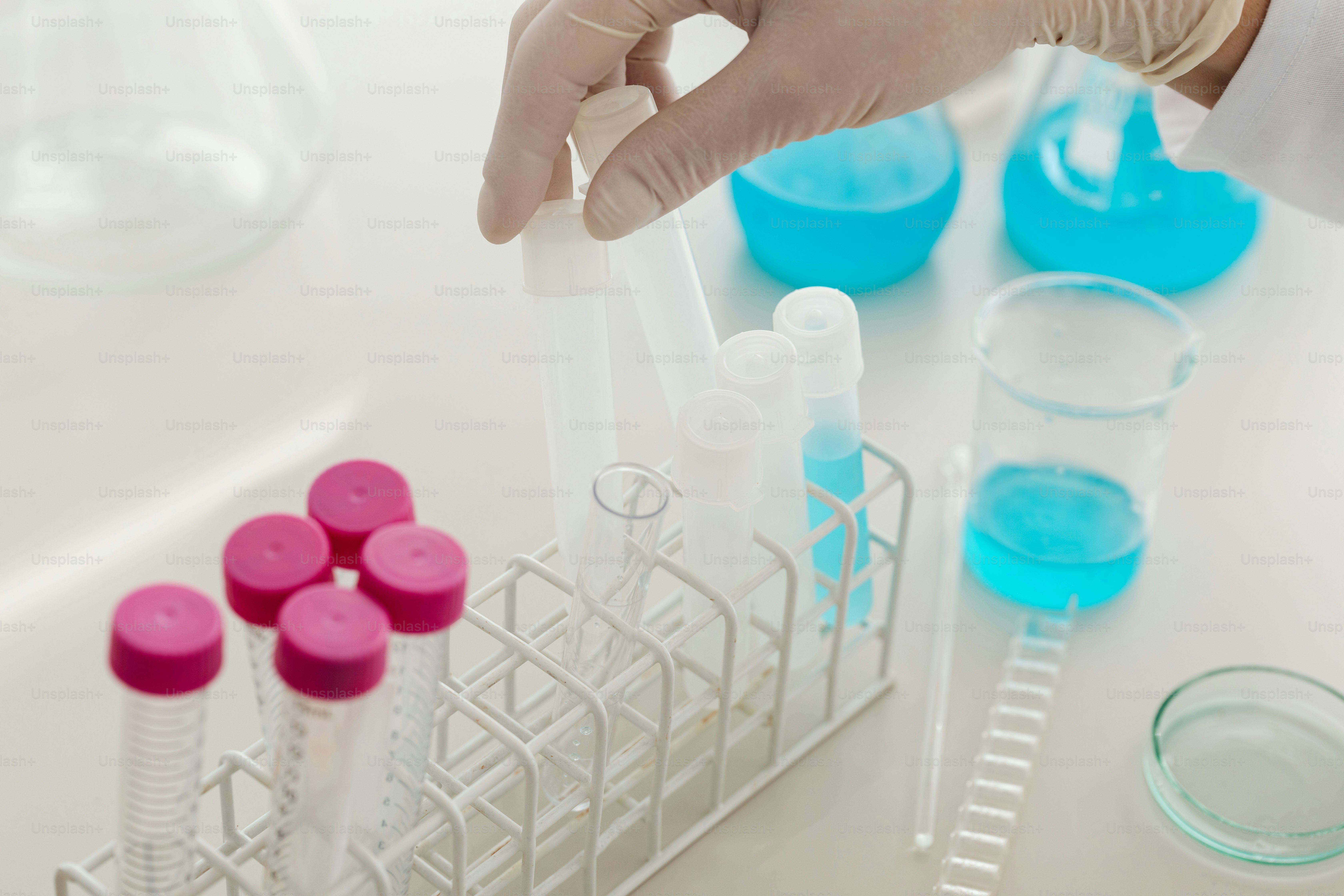 une personne tenant un tuyau devant un rack de tubes à essai