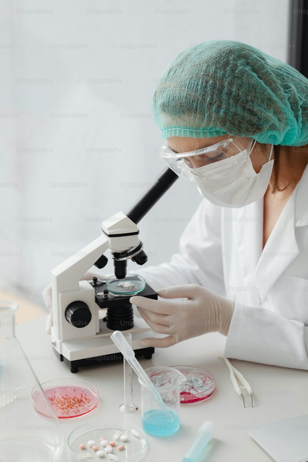 a woman in a white lab coat looking through a microscope
