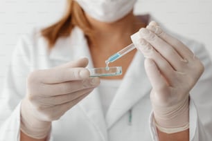 a woman in a white lab coat is holding a tube