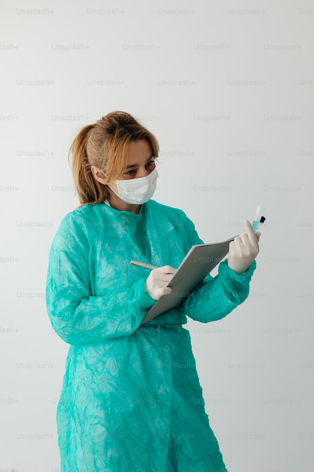 a woman wearing a mask and gown holding a clipboard