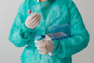 Una persona con un traje verde sosteniendo un contenedor azul