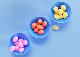 Tre ciotole piene di caramelle su sfondo blu