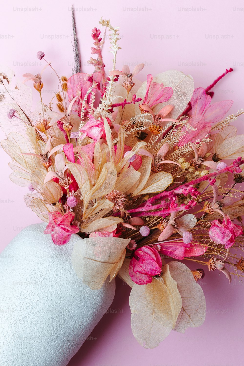 a hand holding a bouquet of flowers on a pink background
