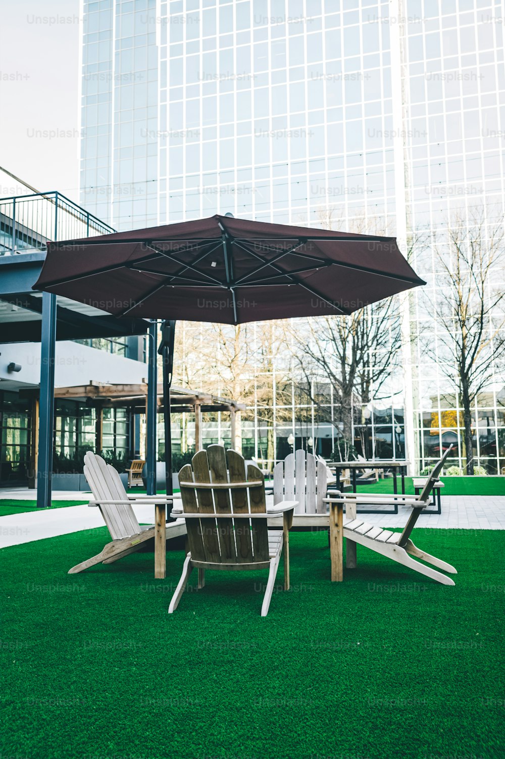 a lawn with chairs and an umbrella in the middle of it