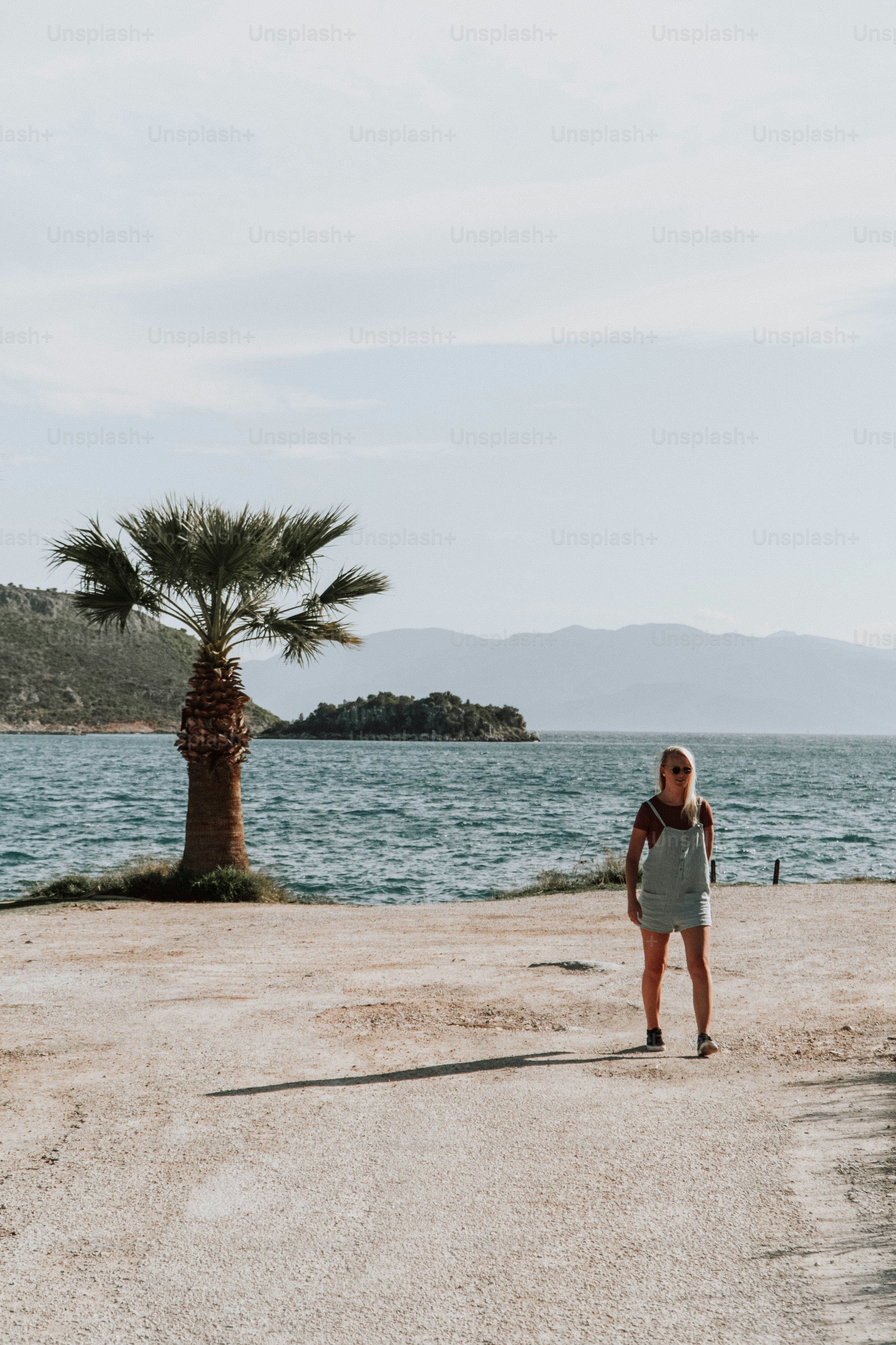 Eine Frau steht am Strand neben einer Palme