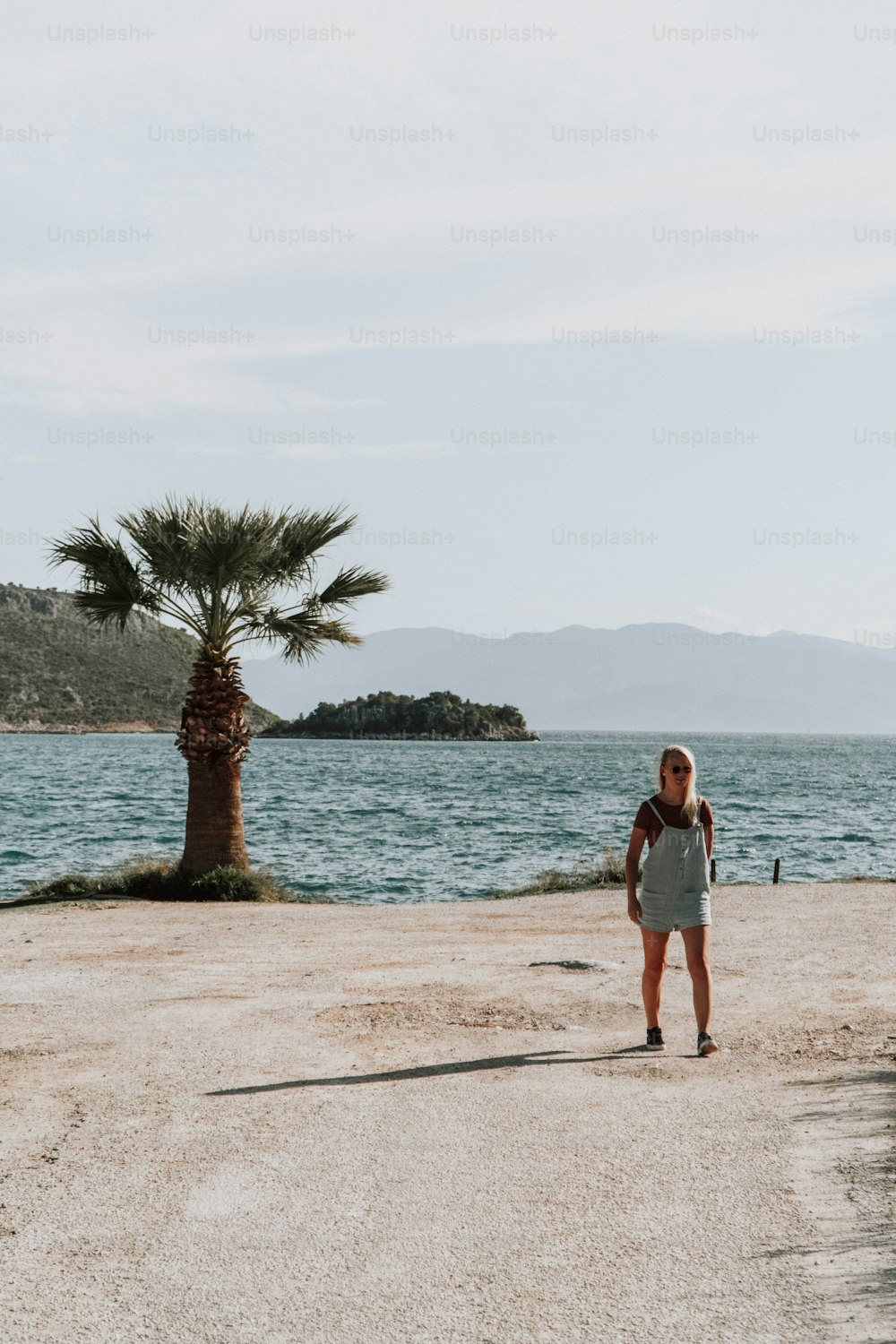 a woman standing on a beach next to a palm tree