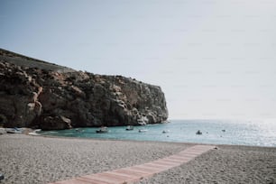 a wooden walkway leading to a beach with boats in the water