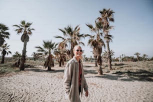 Eine Frau steht auf einem Sandstrand neben Palmen