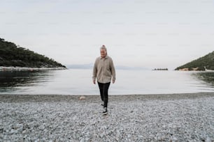 a woman walking on a beach next to a body of water