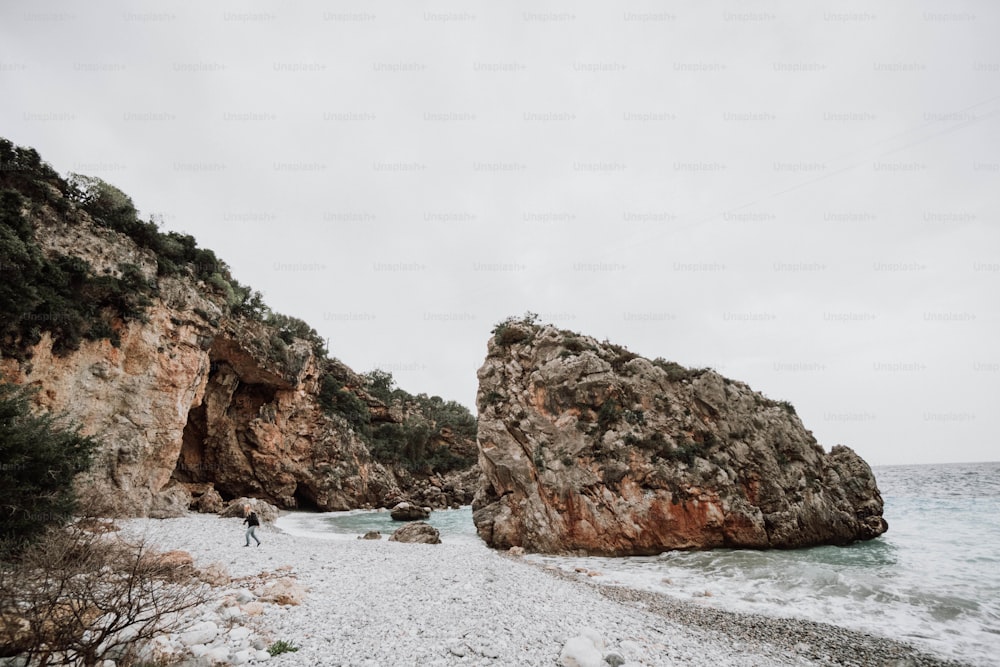 une personne debout sur une plage rocheuse à côté d’un plan d’eau
