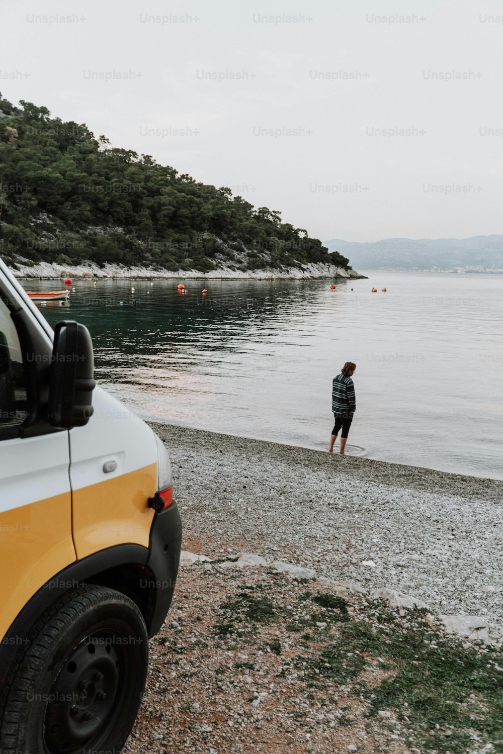 a man standing on a beach next to a van