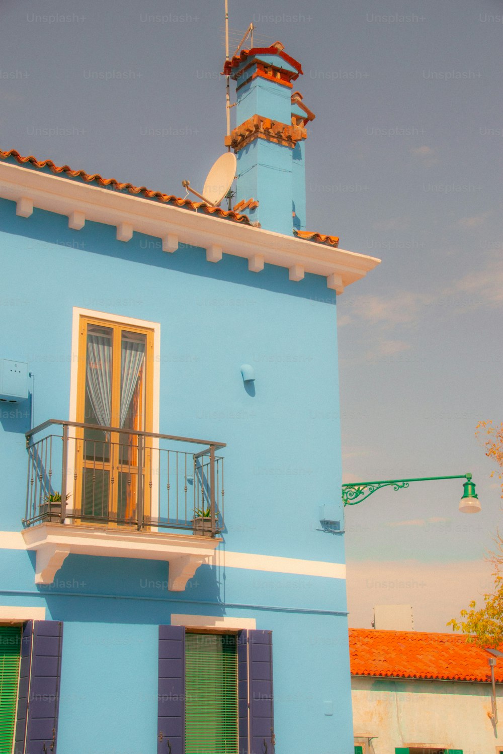 Un edificio azul con una puerta verde y un techo rojo