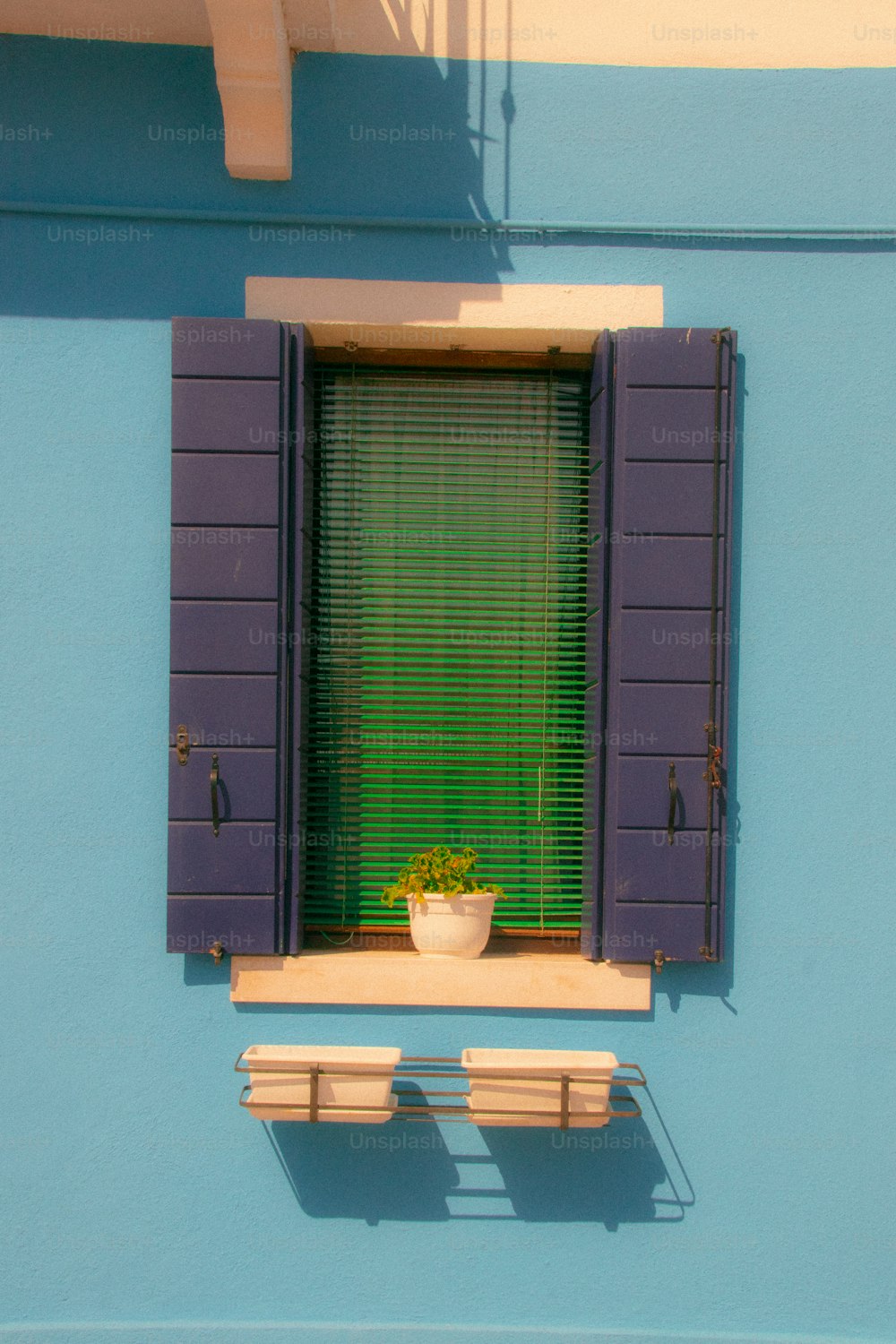 una ventana con persianas azules y una planta en maceta