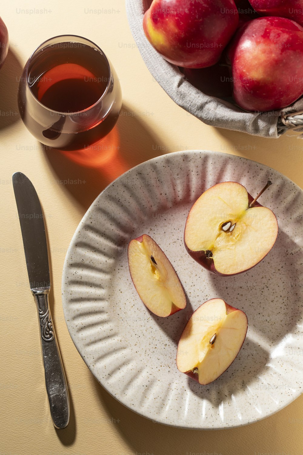 a bowl of apples and a plate of apples next to a cup of tea