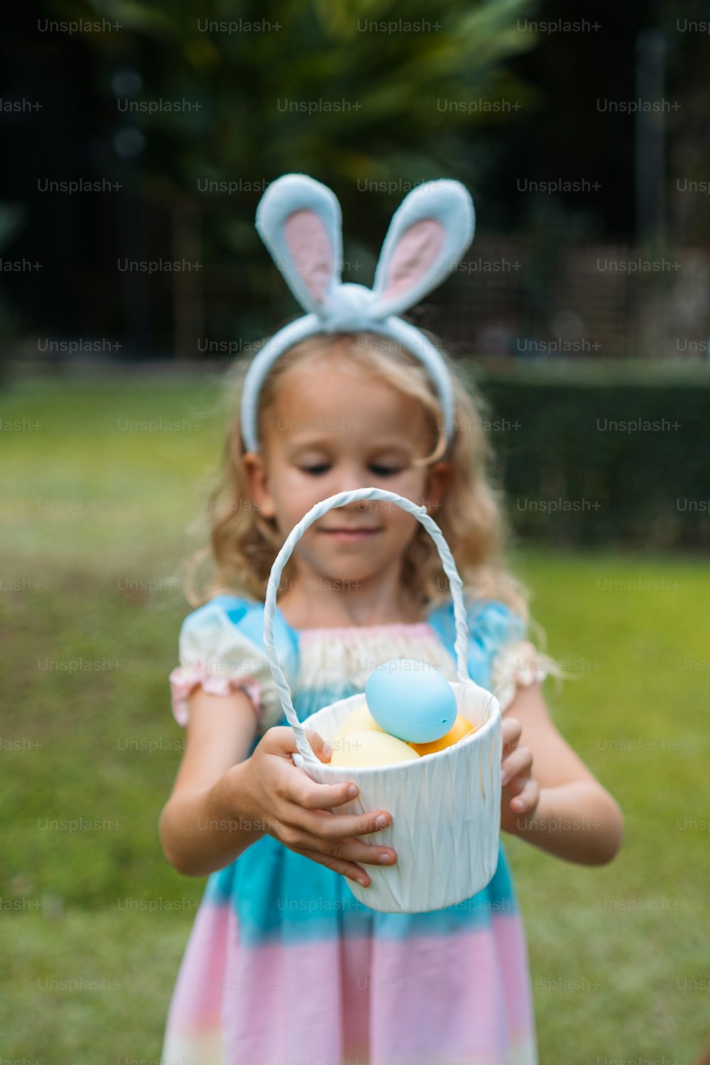 a little girl holding a basket with eggs in it
