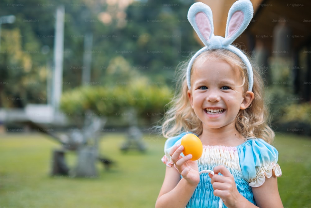 a little girl in a blue dress holding an orange