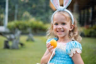 a little girl in a blue dress holding an orange